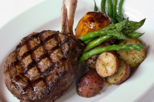 Right off the grill filet steak with bone, topped with seasoned potatoes, asparagus and zucchini.